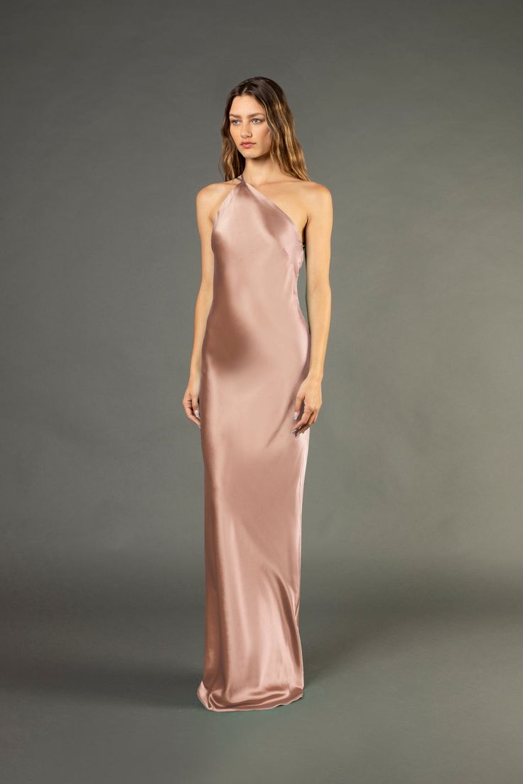 a woman in a long pink dress with one shoulder and an asymmetrical neckline