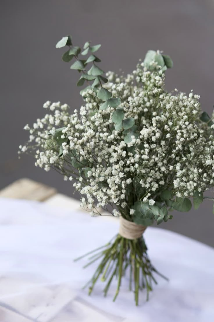 a bouquet of baby's breath sitting on top of a white cloth covered table