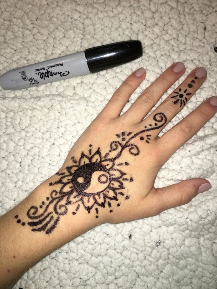 a woman's hand with henna tattoos on it and a pen next to it