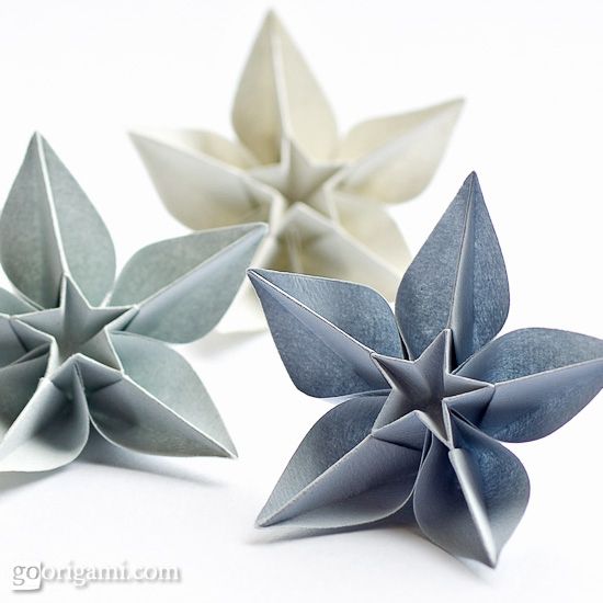 three origami flowers sitting next to each other on top of a white surface