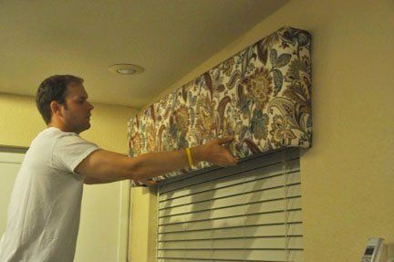 a man is painting the blinds in his living room