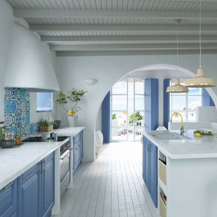 a large kitchen with blue cabinets and white counter tops, along with an archway leading to the dining room