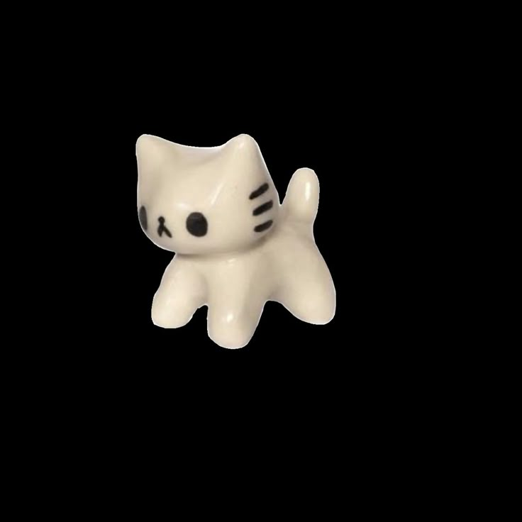 a white cat figurine sitting on top of a black surface