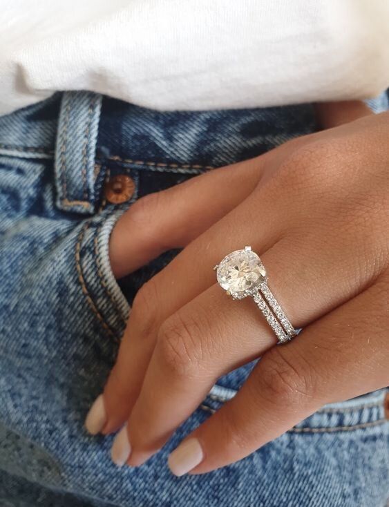 a close up of a person wearing a ring on their finger and holding onto her jeans