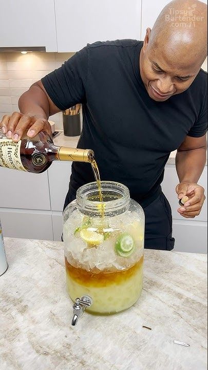 a man pours a drink into a mason jar filled with ice and lime slices