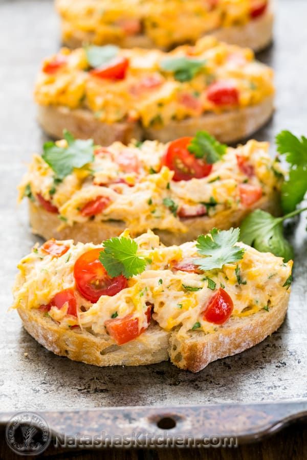 three pieces of bread with different toppings on them sitting on a table next to some parsley