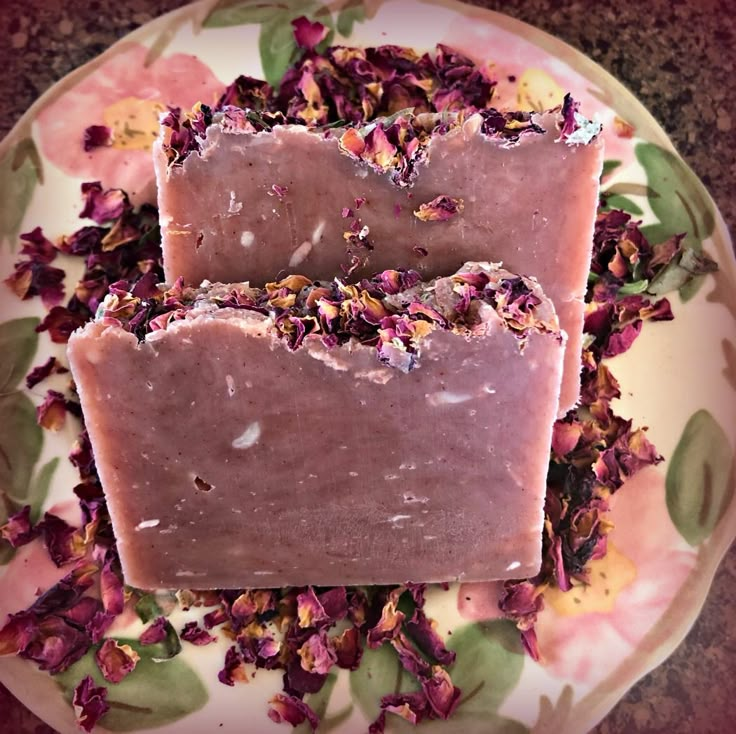 two bars of soap sitting on top of a plate with pink and green flowers around it