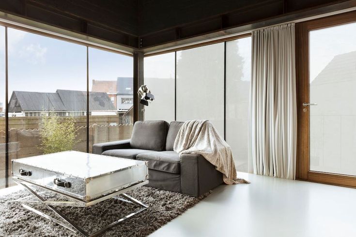 a living room filled with furniture next to large windows and a white rug on the floor