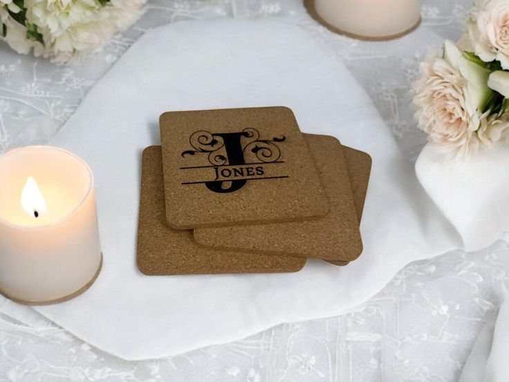 three personalized coasters sitting on top of a table next to a lit candle