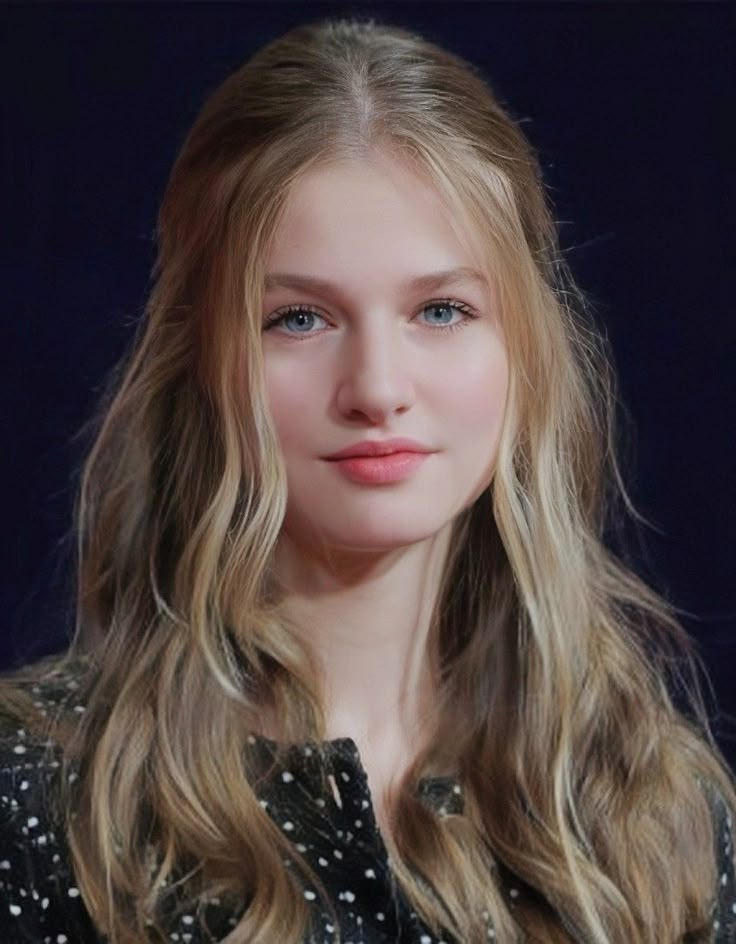 a woman with long blonde hair wearing a black shirt and polka dot blouse looking at the camera