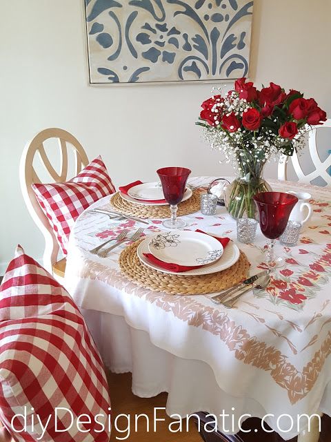 a dining room table set for two with red and white placemats on it