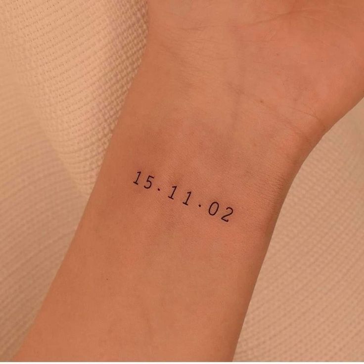 a woman's wrist with a date tattoo on the left side of her arm