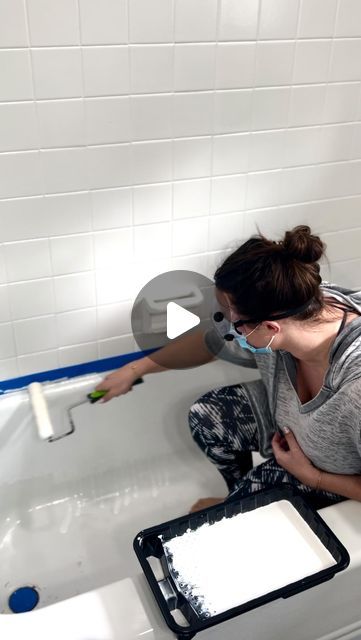 a woman kneeling down in a bathtub while using a shower head cleaner to clean the tub