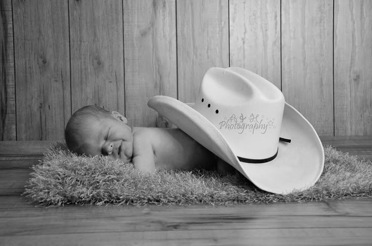 a black and white photo of a baby wearing a cowboy hat