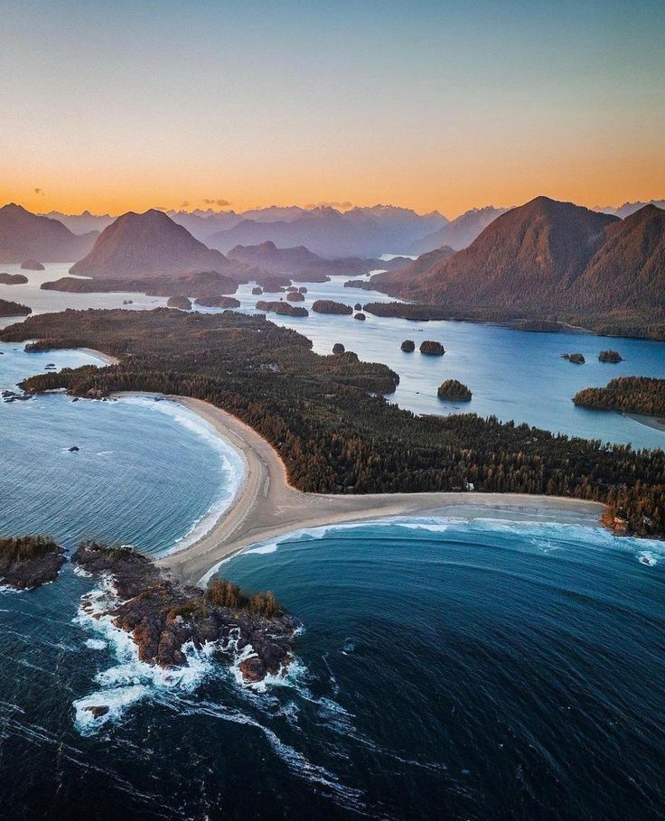 an aerial view of the ocean with mountains in the background and water on both sides