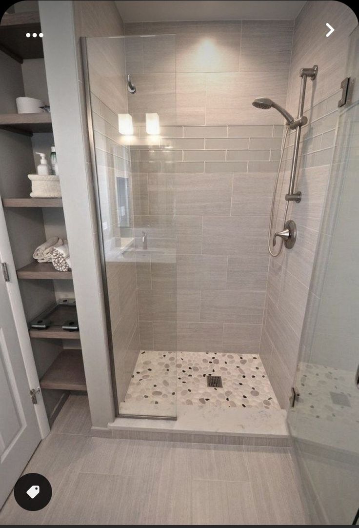 a walk in shower sitting next to a white door and shelves on either side of it