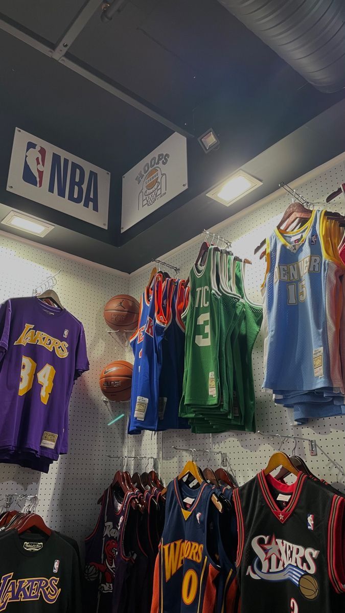 several jerseys are hanging on the wall in a basketball shop, and there is a sign above them that says n b a