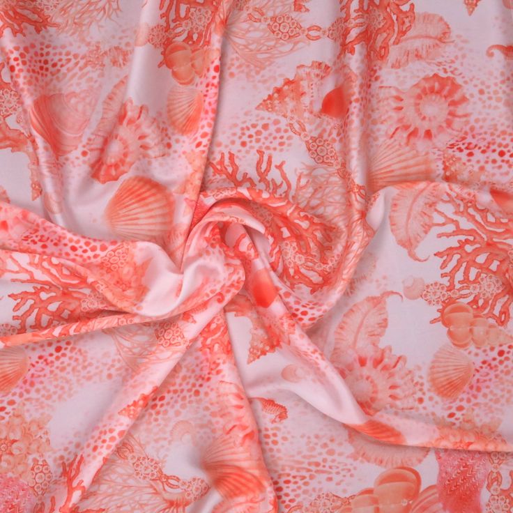 an orange and white floral print fabric with coral colored flowers on the bottom half of it