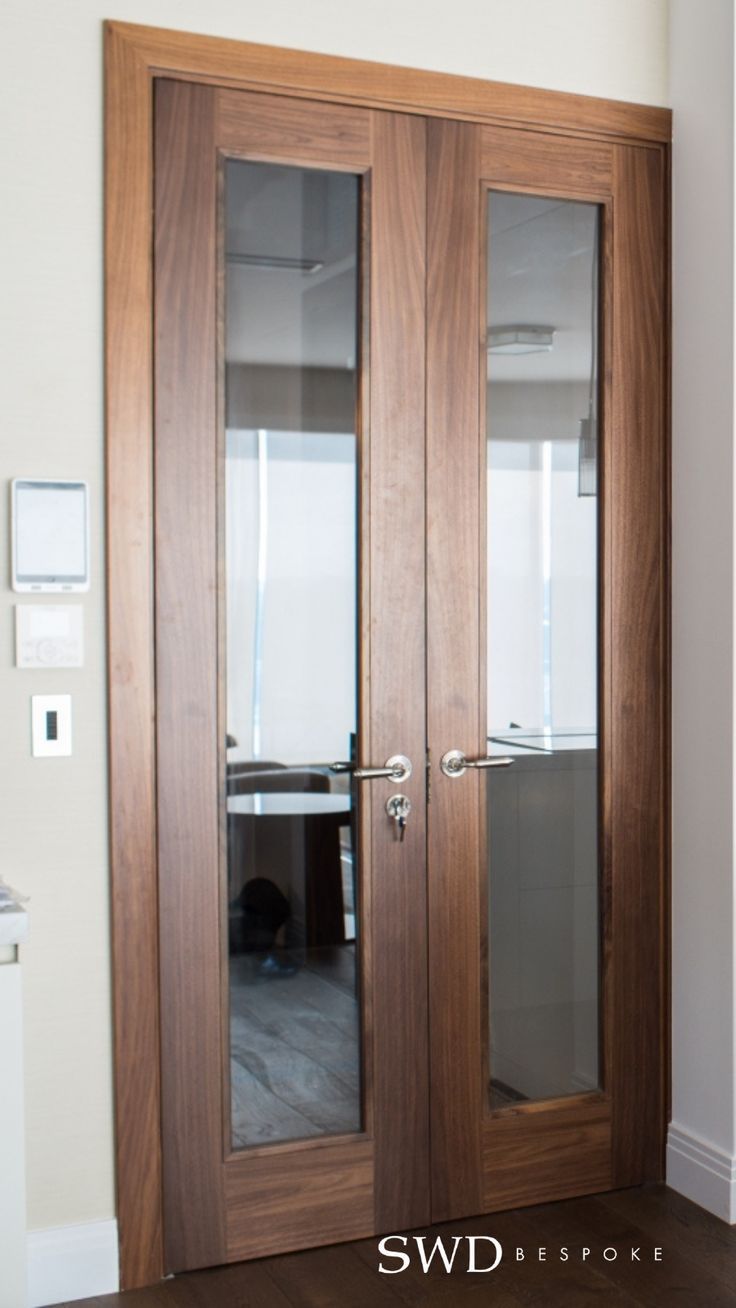 an empty room with two doors and a desk on the other side in front of it