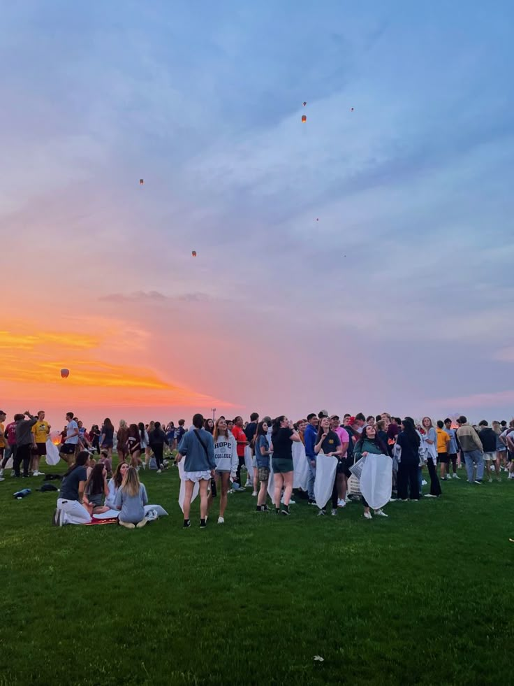 a group of people standing on top of a lush green field under a colorful sky