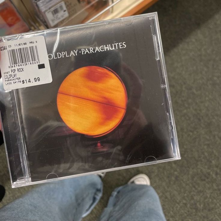 a person holding up a cd case in their hand with an orange disk on it