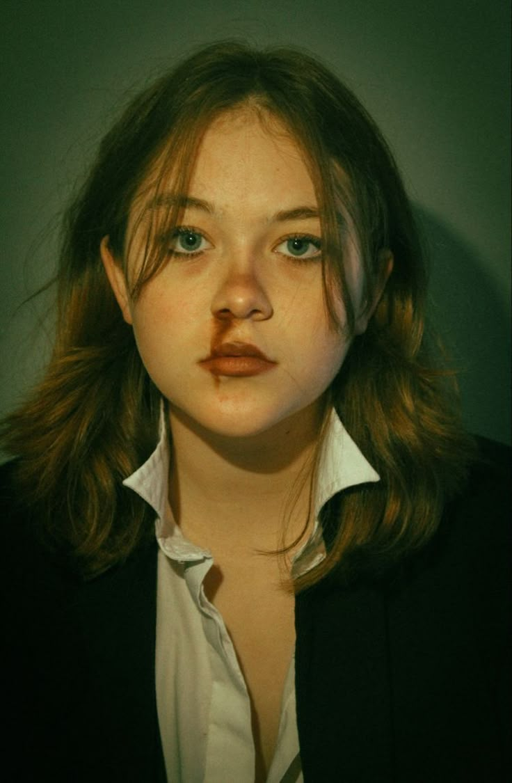 a woman with long brown hair wearing a black blazer and white collared shirt