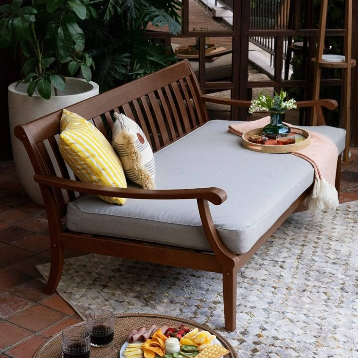 a wooden bench sitting on top of a patio next to a table filled with food