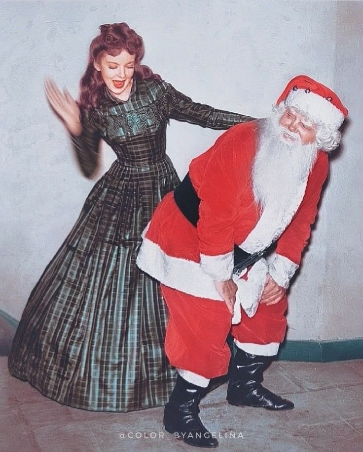 a man dressed as santa claus is dancing with a woman in a long green dress