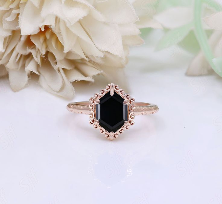 a black diamond ring sitting on top of a white flower