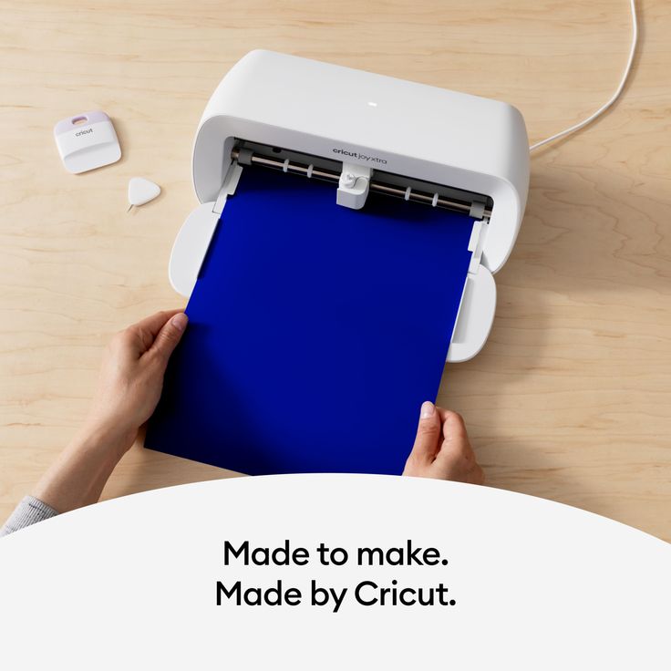 a person using a machine to make a blue piece of paper with the words made by cricut on it