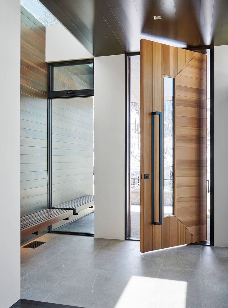 an open wooden door in front of a white wall and wood paneled entryway