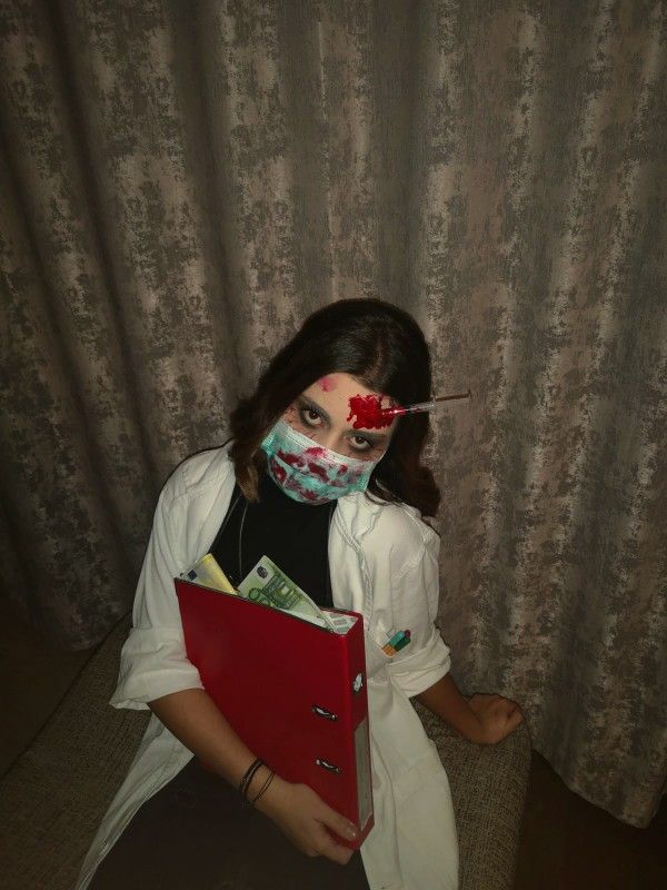 a woman with blood on her face holding a binder in front of a curtain