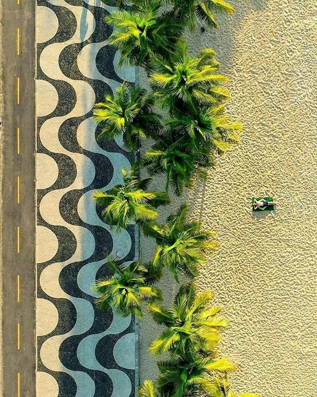 an aerial view of a beach with palm trees on the sand and two boats in the water