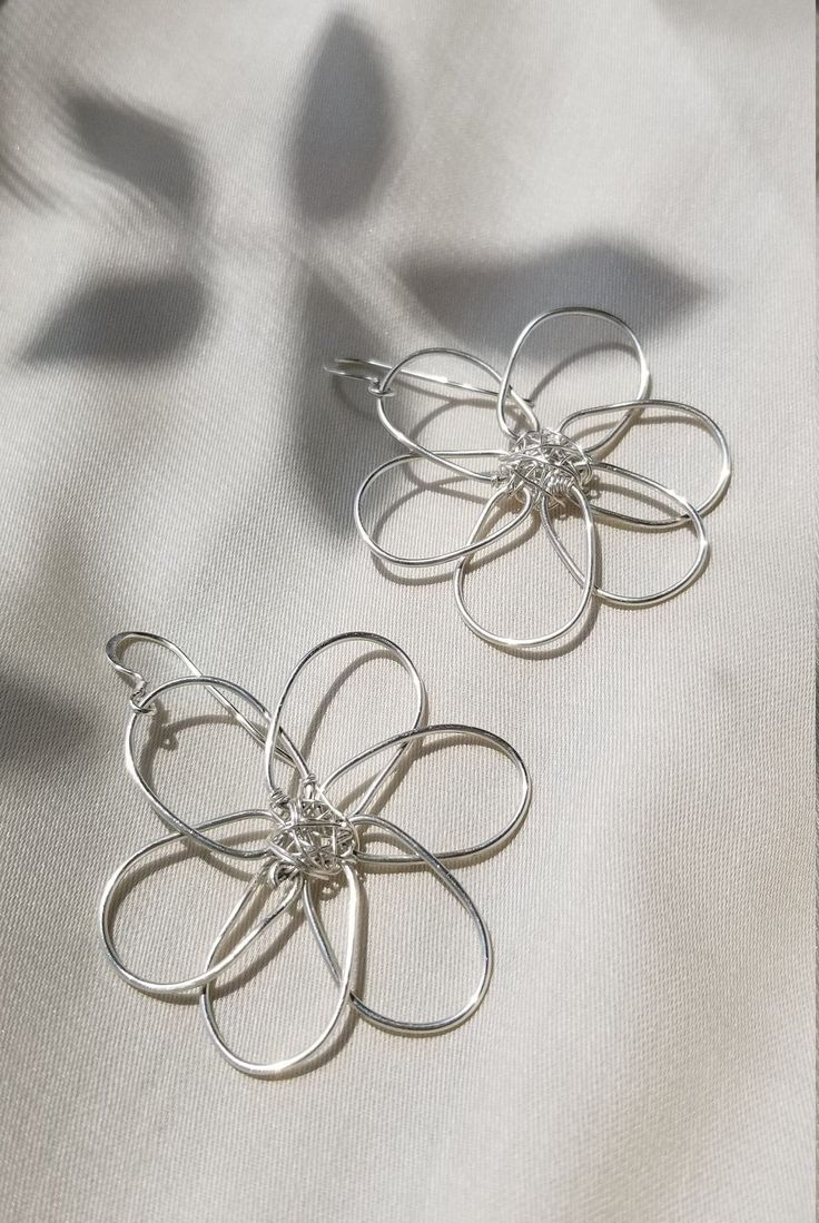 Flower power! Bold, floral wire earrings inspired by summer daisies. Stand out from the crowd with these fun statement pieces. Simple yet stunning. Lightweight, shiny, and perfect for long wear. Made by hand from your choice of silver or gold plated wire. The flower center is wrapped with either .999 fine silver wire or fine gold wire.  Ear hooks are either .925 sterling silver or gold fill, so this design may be enjoyed by sensitive ears. Earrings measure approx. 2 inches across. Drop is 1.5 in Metal Flower Charm Earrings For Spring, Summer Flower Earrings In Sterling Silver For Gift, Sterling Silver Flower Earrings For Summer, Summer Flower Sterling Silver Earrings For Gift, Whimsical Spring Flower Earrings With Ear Wire, Sterling Silver Flower Earrings For Summer Gift, Summer Flower Shaped Metal Earrings, Elegant Silver Flower Earrings For Summer, Handmade Metal Flower Earrings For Summer