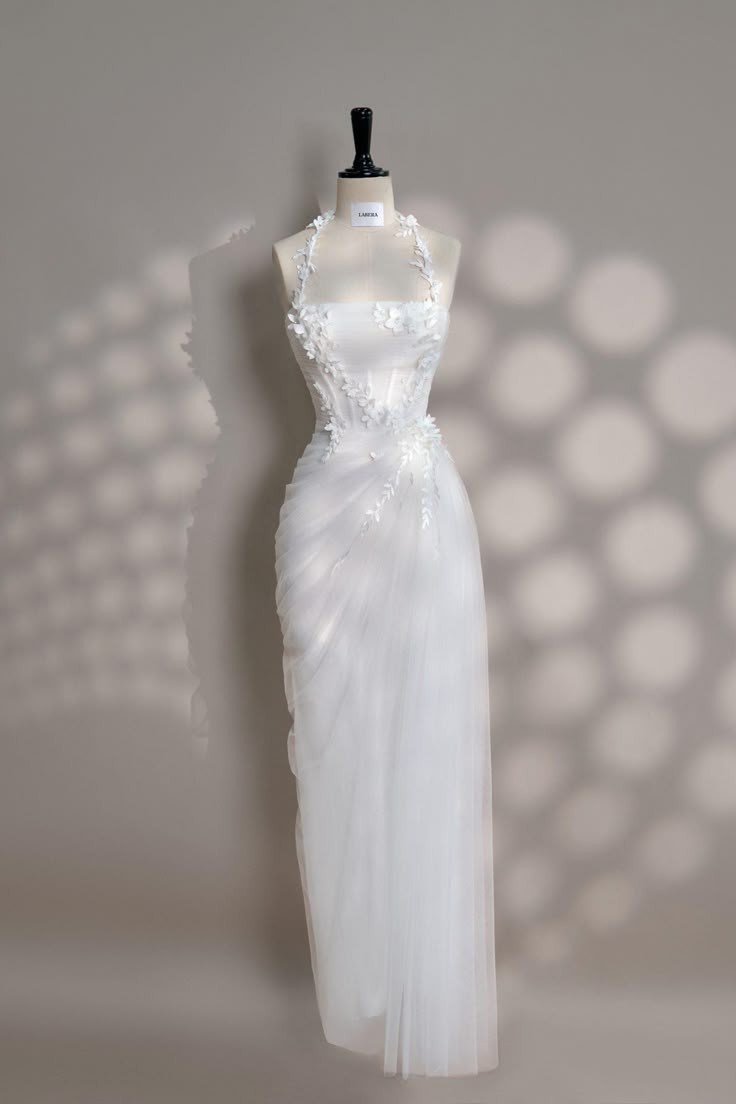 a white dress on a mannequin stand in front of a wall