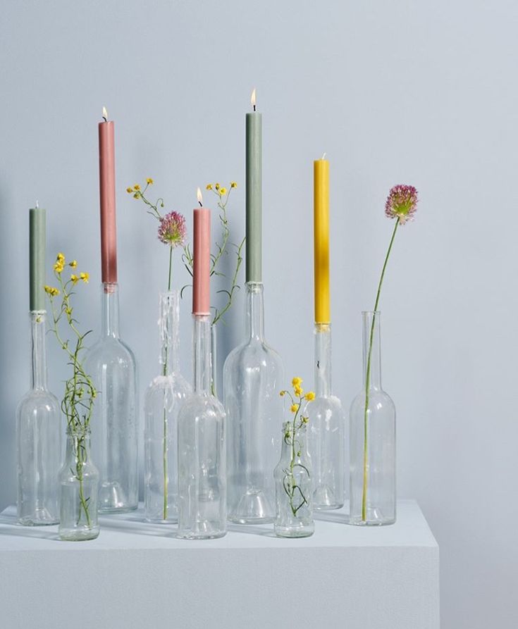 several vases with flowers and candles in them