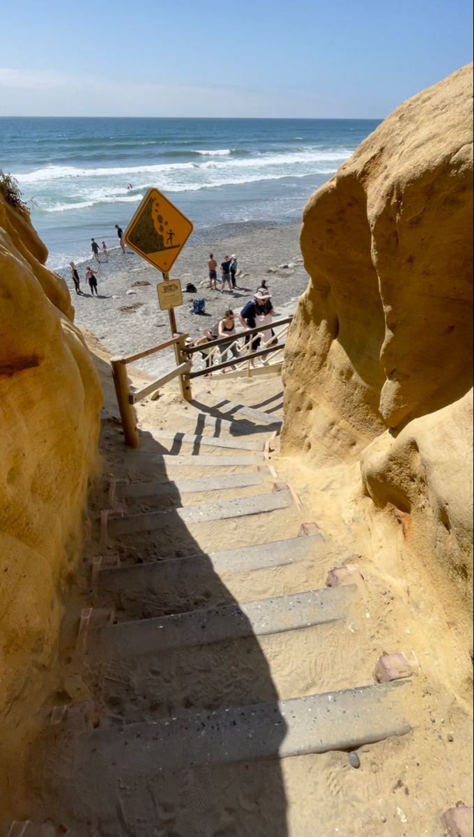 stairs lead down to the beach with people swimming in the water