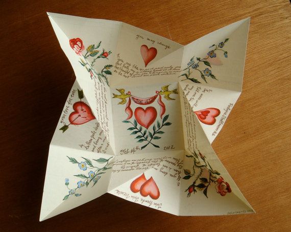 an origami flower with hearts on it sitting on top of a wooden table