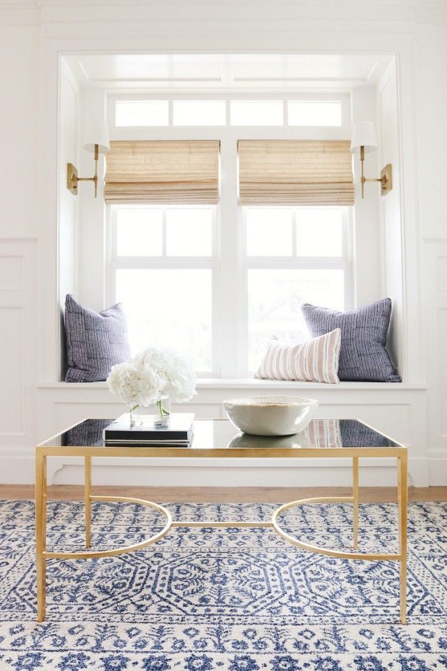 a coffee table in front of a window with blue and white rugs on it