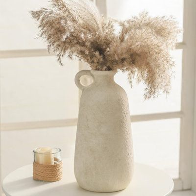 This set of two modern handmade ceramic vases in off-white with a matte finish is perfect for any decor. Their sculptural design with a frosted sand texture adds elegance to your home. Use them as centerpieces for fresh flowers, dried florals, or pampas grass. Ideal for living rooms, bedrooms, dining areas, and offices, these vases are a stylish addition to any space. They also make a thoughtful gift for weddings, housewarmings, and other special occasions. Lark Manor™ | Lark Manor™ Handmade Mo… Modern Vases Decor, Pampas Vase, Vase Pampas, White Bungalow, Fake Flowers Decor, Large Floor Vase, Sand Texture, Farmhouse Vase, Boho Vase