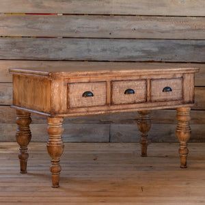 an old wooden table with three drawers