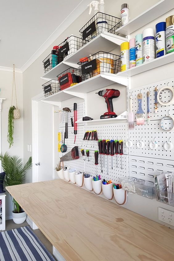 an organized craft room with pegboard and shelves