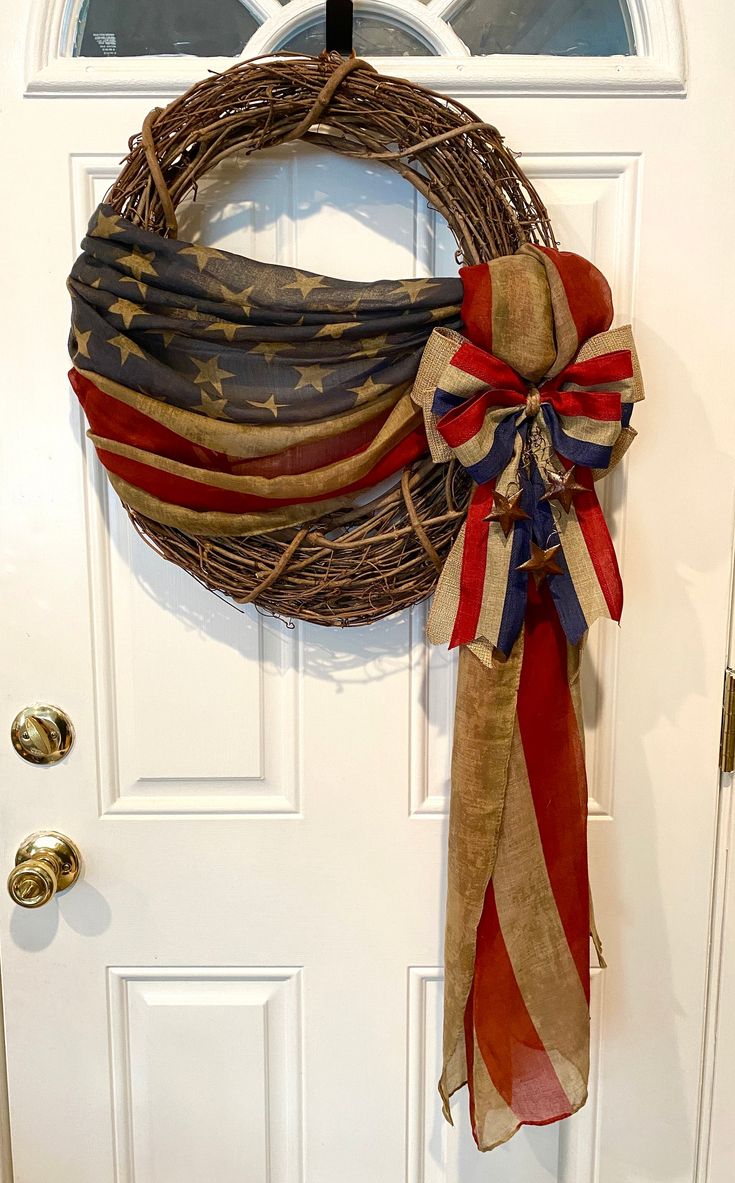 a patriotic wreath hanging on the front door with an american flag ribbon tied around it