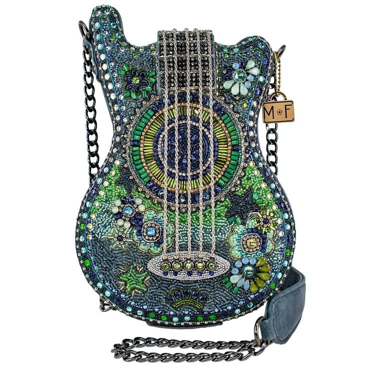 A dazzling hand beaded crystal jeweled shoulder bag that strikes a chord between glamour and musical charm. Shaped like a guitar with intricate blue and green beaded work, this handbag is a visual masterpiece. A must-have for the fashionable musician in you! 6.5 x 1.75 x 9" Strap Length End to End: 46" Strap Drop: 21" Non-removable padded-shoulder chain strap, magnet closure, inside pocket, fits a cell phone, vegan leather       This is a handmade item, each one an individual work of art. Slight variations may occur  ** We are Authorized Retailers for Mary Frances’ Stunning Pieces of Art Handbags ** GUARANTEED AUTHENTIC. ORIGINAL, NEW WITH TAGS, READY TO SHIP. Custom Dart Board, Mary Frances Bags, Mary Frances Handbags, Novelty Handbags, Novelty Purses, Beaded Work, Mary Frances, Best Handbags, Handmade Purses