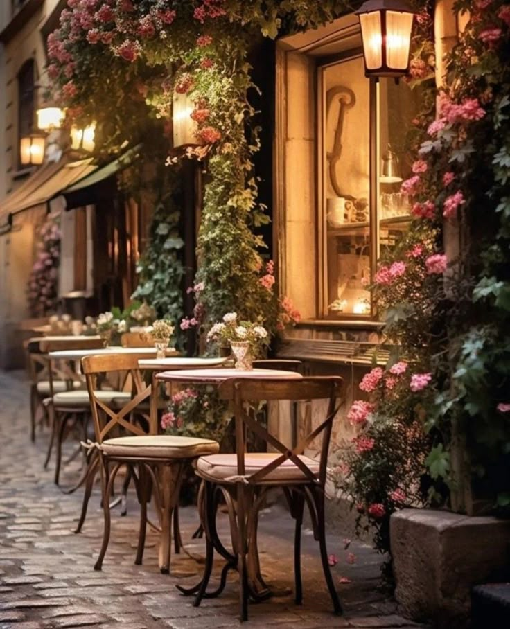 tables and chairs are lined up on the side walk in front of a building with flowers growing all over it