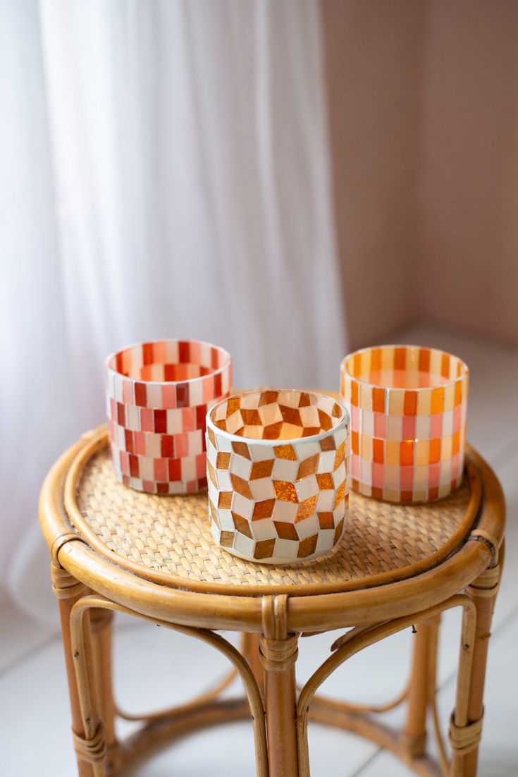 three orange and white checkered cups on a wicker table