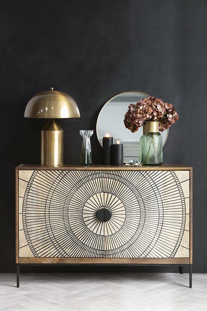 a sideboard with a mirror and vases on it next to a table lamp