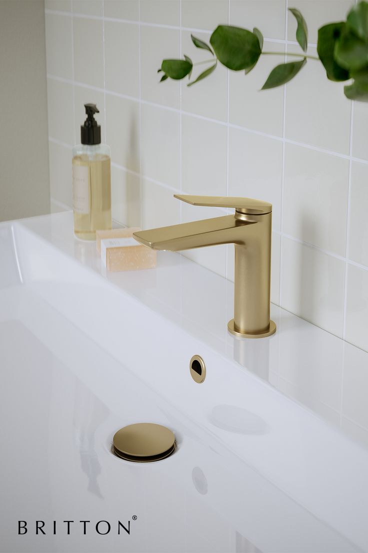 a bathroom sink with a gold faucet and soap dispenser