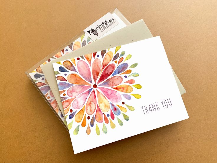 two thank cards with watercolor designs on them, one is folded and the other has a note attached to it