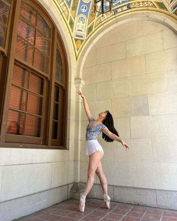 a woman is posing in front of a building with an arched doorway and painted ceiling